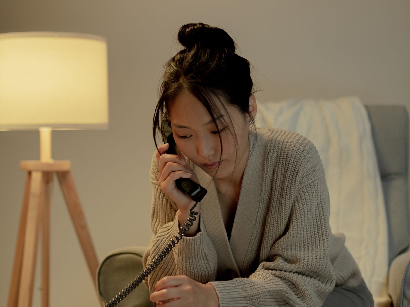 A woman sitting indoors, talking on the phone.